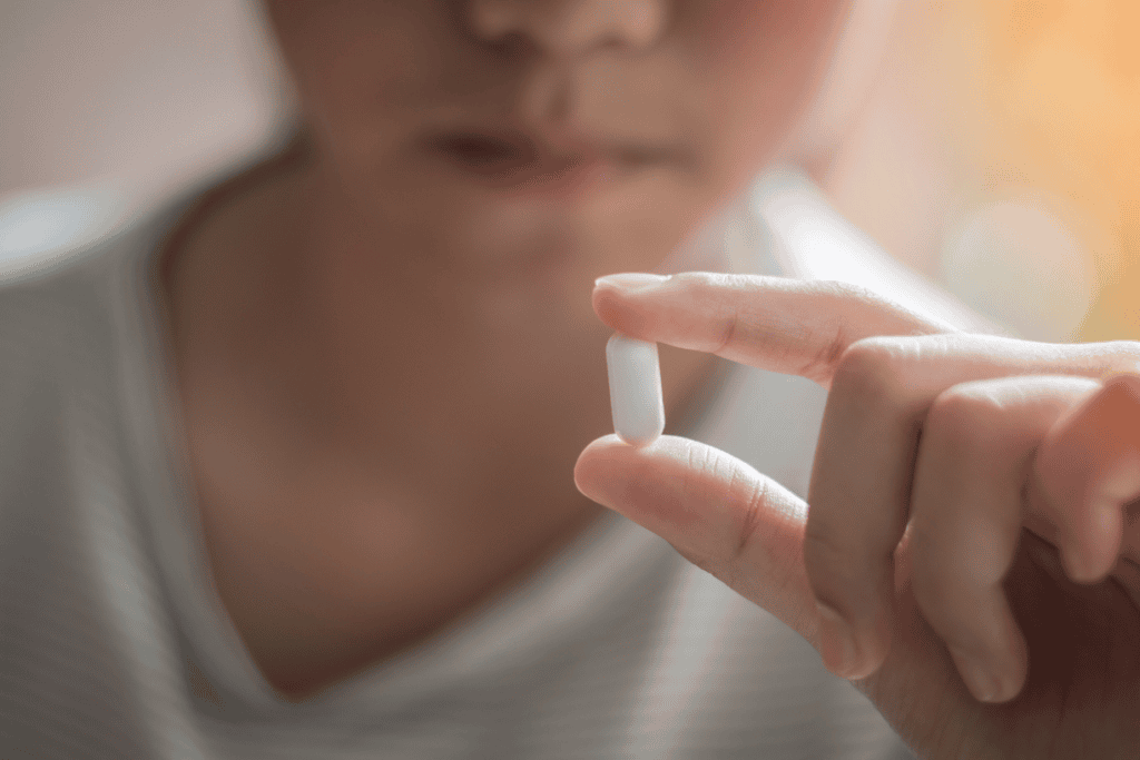 close-up of a person holding a single white capsule close-up of a person holding a single white capsule