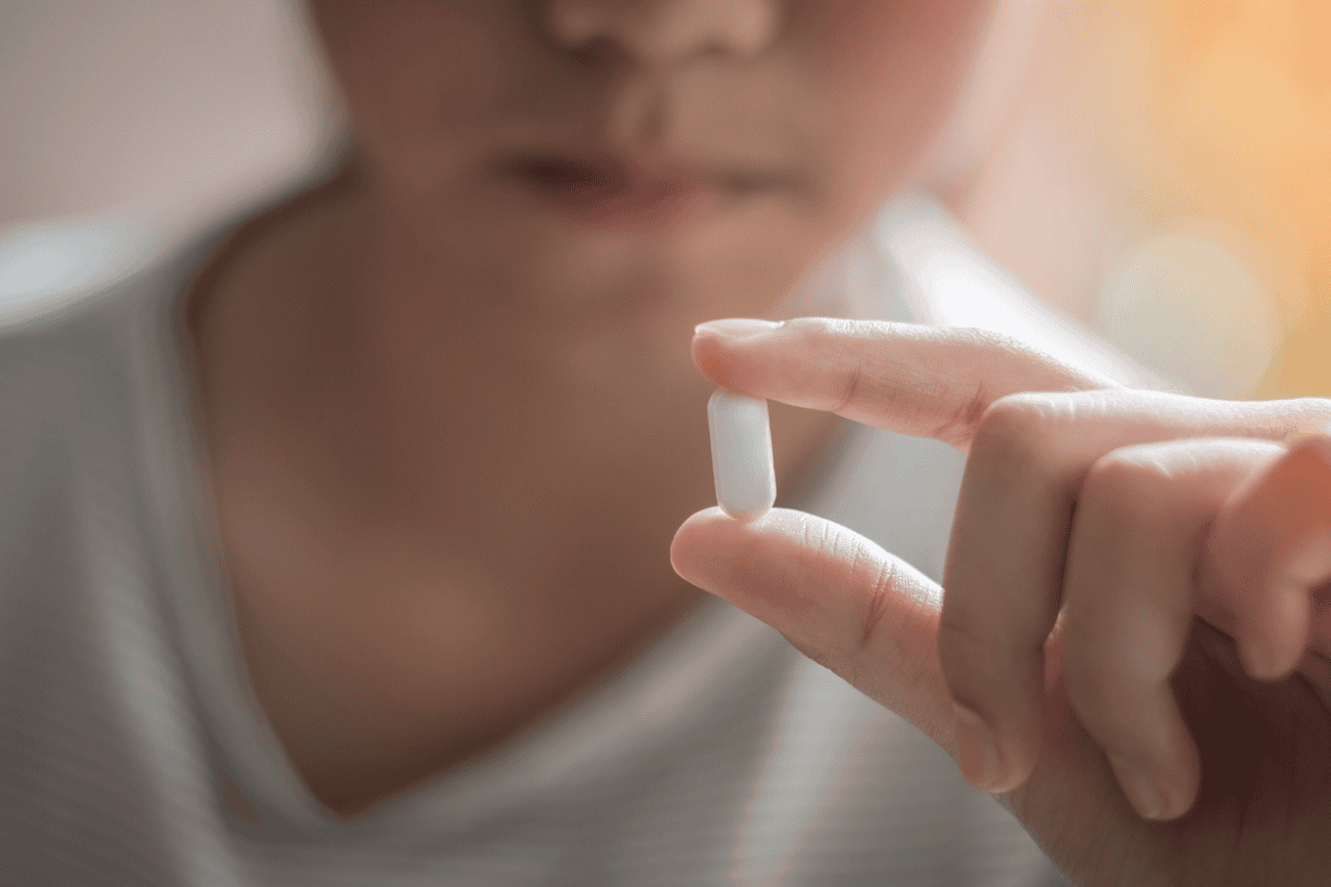 close-up of a person holding a single white capsule