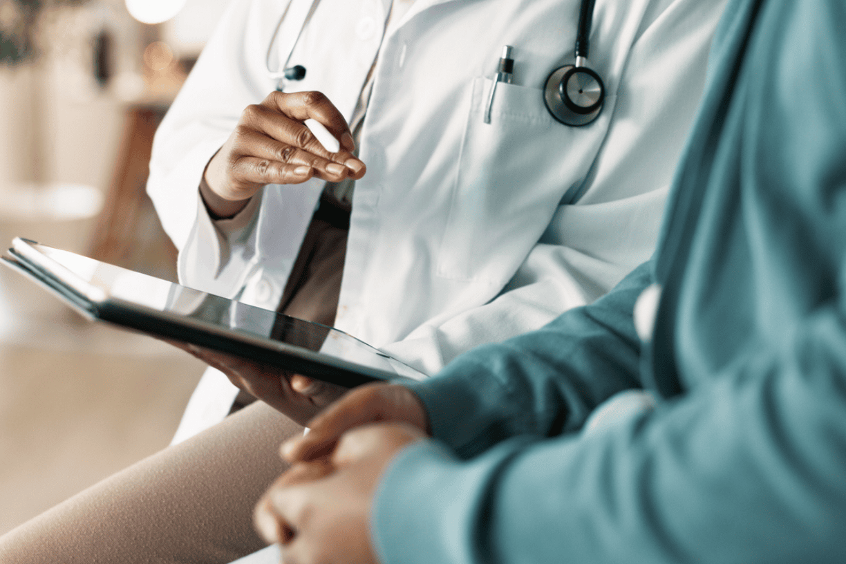 doctor with a stethoscope reviewing a chart with a patient