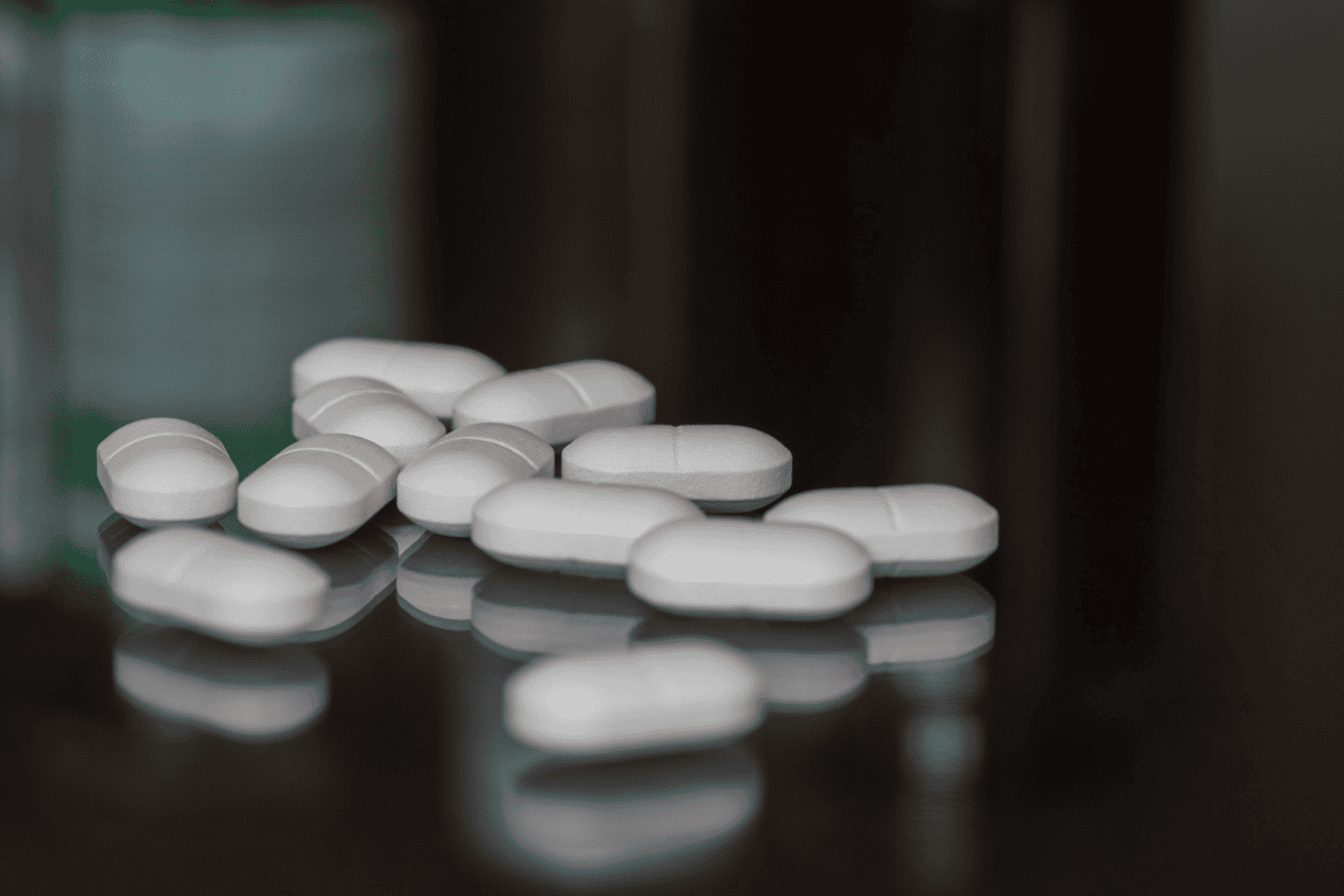 white pills scattered on a dark surface