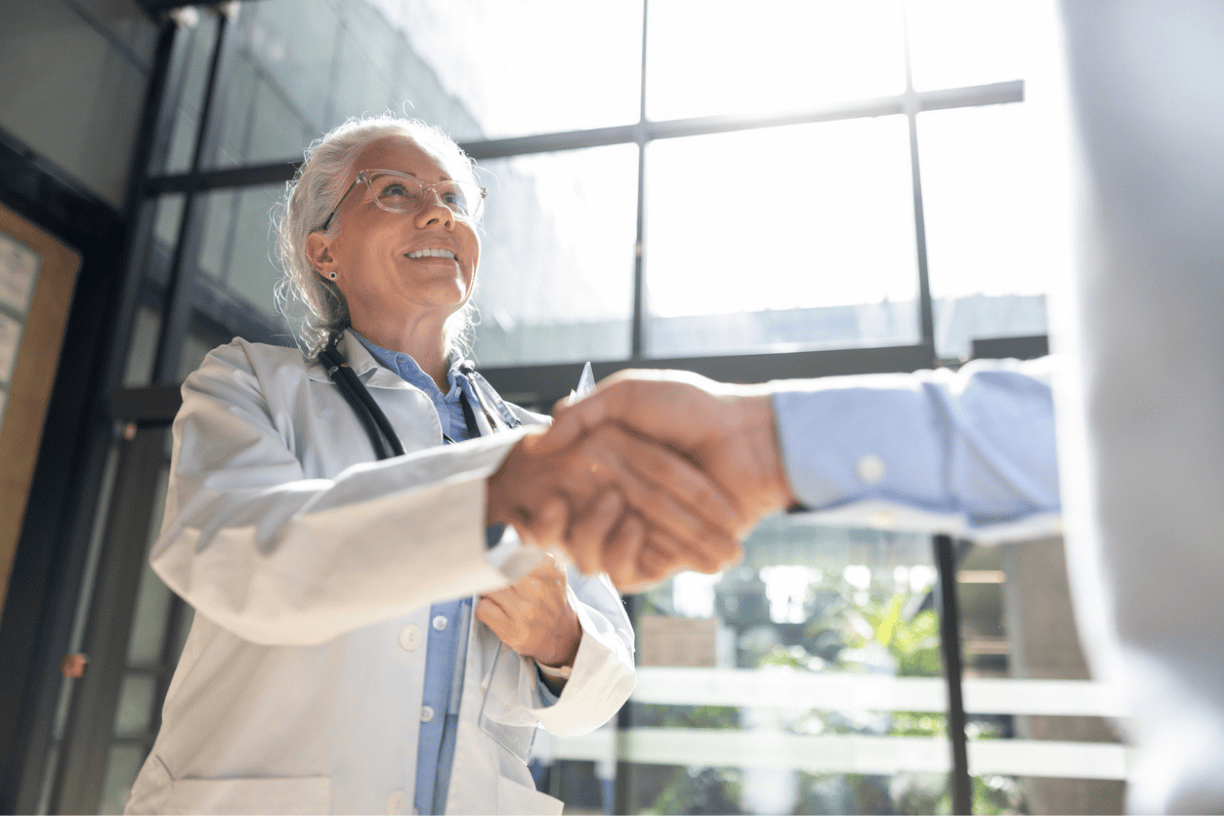 doctor shaking hands with a patient in a bright office