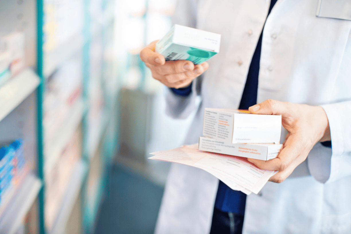 pharmacist standing in aisle holding prescriptions