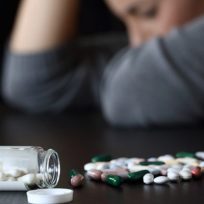 Woman-sitting-at-a-table-with-a-close-up-of-pills