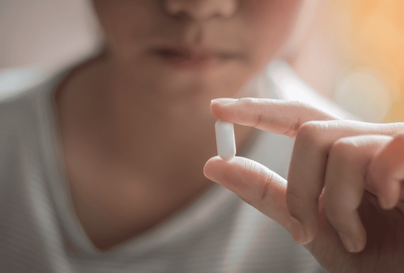 close-up of a person holding a single white capsule