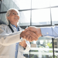 doctor shaking hands with a patient in a bright office