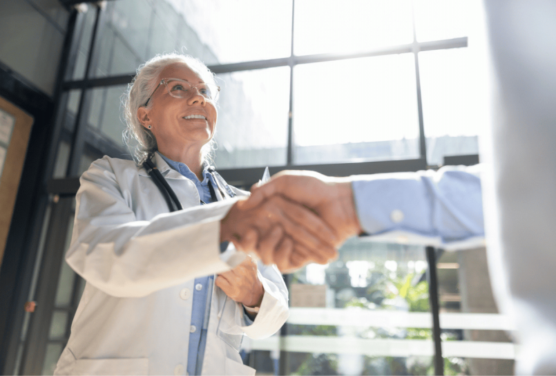 doctor shaking hands with a patient in a bright office