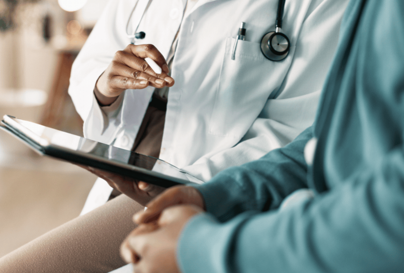 doctor with a stethoscope reviewing a chart with a patient