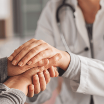 person resting a comforting hand on someone's arm during a medical visit