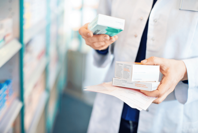 pharmacist standing in aisle holding prescriptions