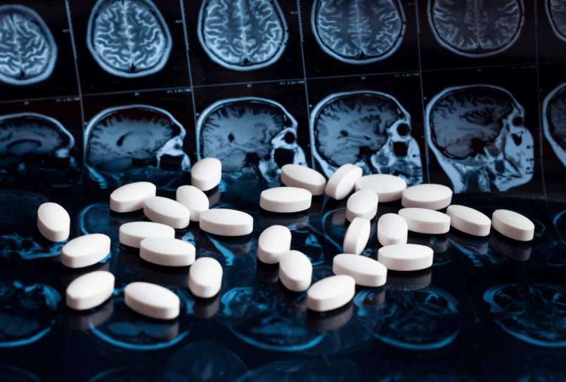 white pills scattered across a set of brain scan images